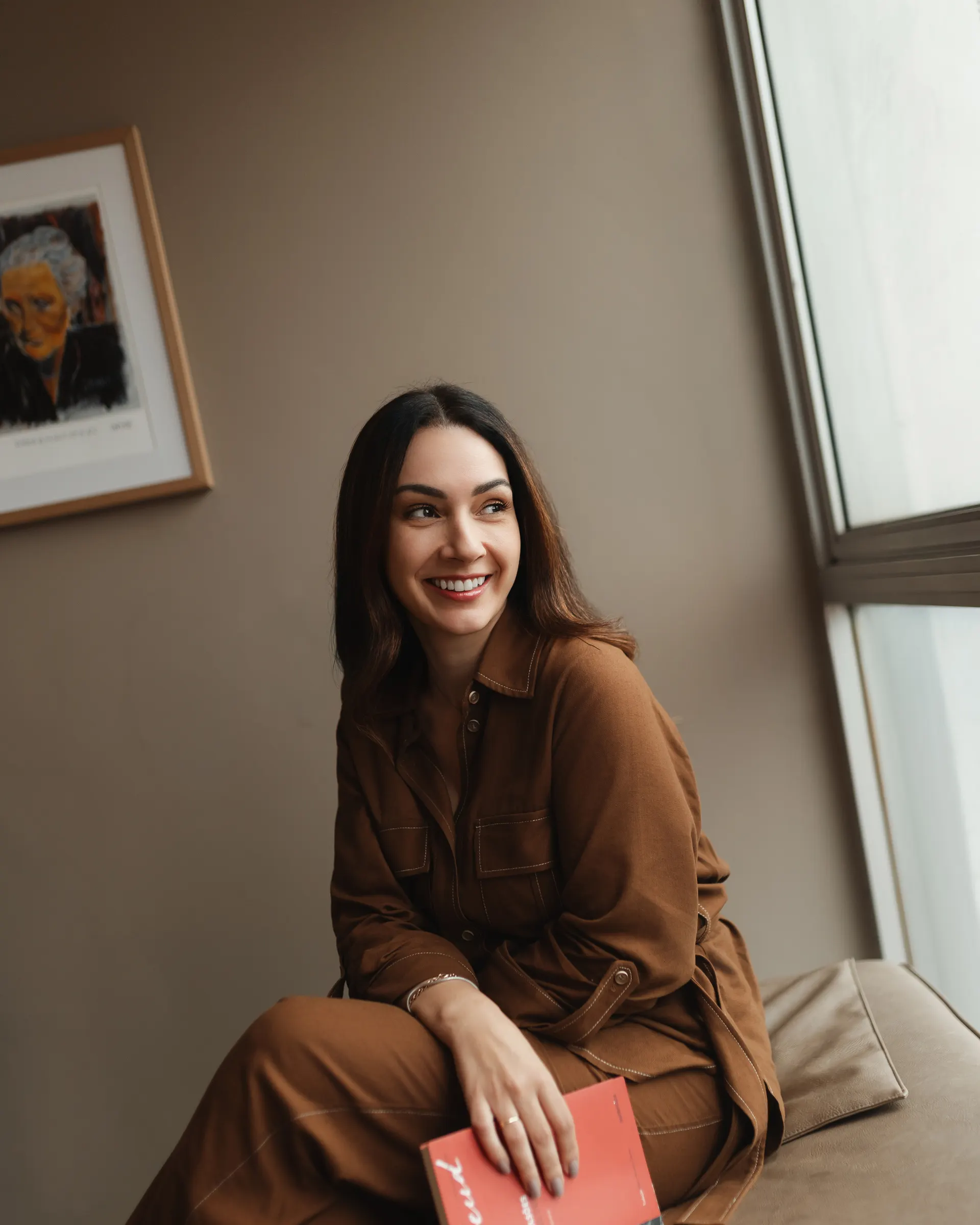 Gabriela Vargas sorrindo, com um livro vermelho na mão